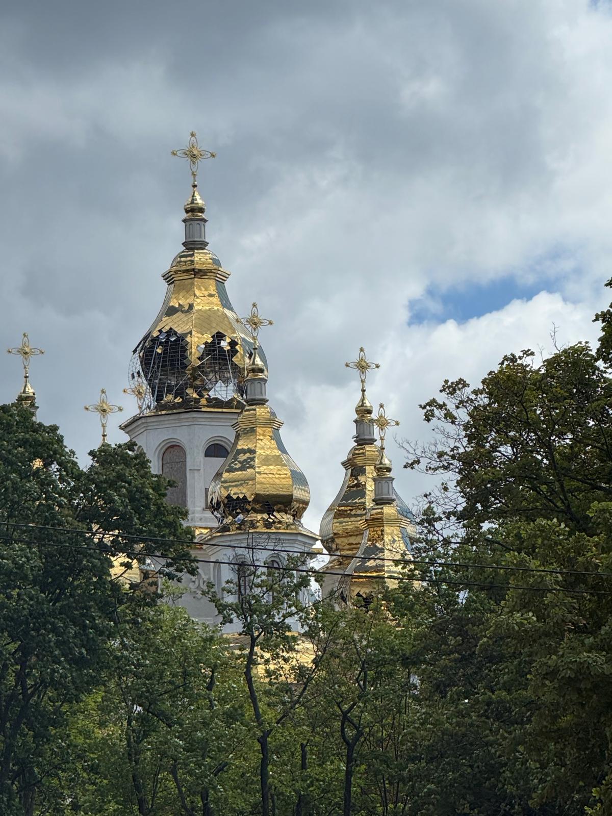 Foto der Kirche der Heiligen Myrrheträgerinnen mit einem prunkvoll vergoldeten Dach, wie es bei orthodoxen Kirchen üblich ist. Allerdings wurden die Türme durch den Krieg ebenfalls teilweise zerstört.