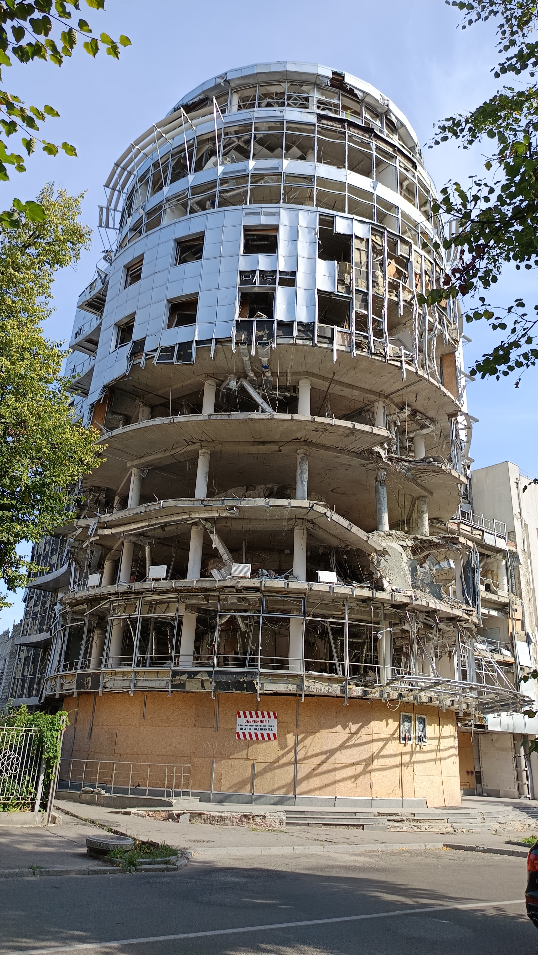 Hohes Gebäude, bei dem die Wände weg gesprengt und die Fenster zerstört sind.