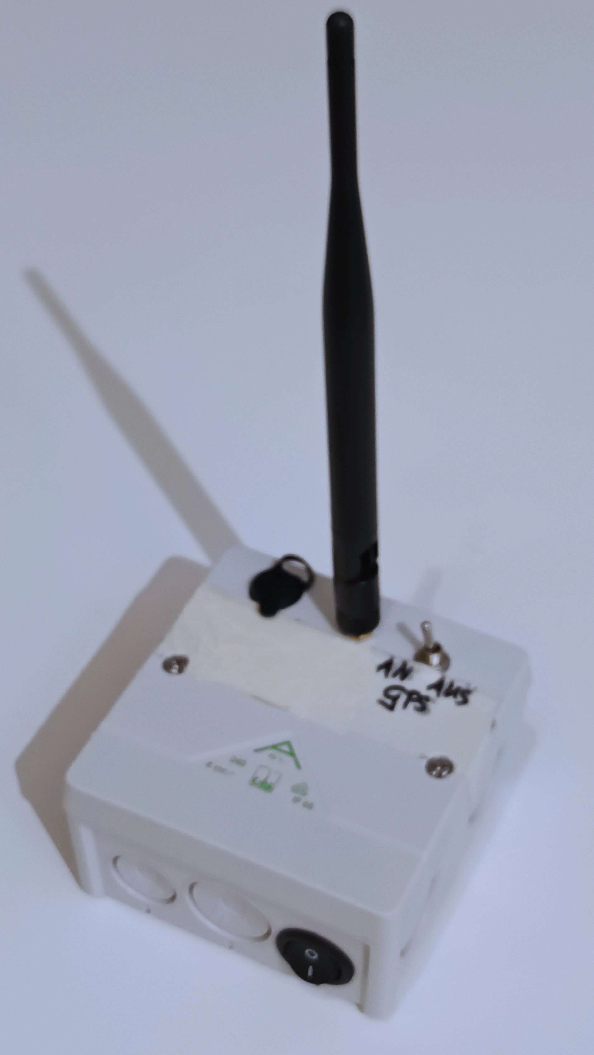 Foto einer Hand großen Kiste, aus der eine große schwarze 
Antenne nach oben ragt.