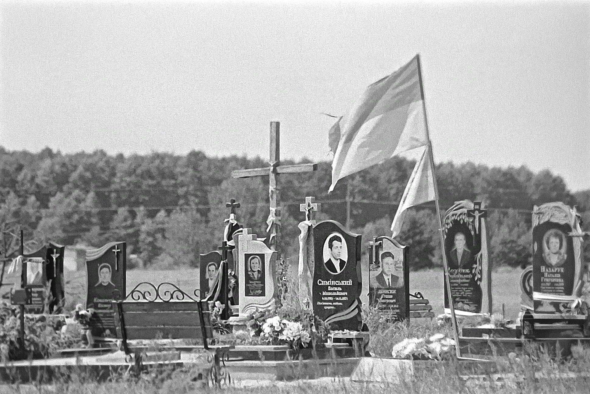 Foto eines neu angelegten Friedhofes über dem die Ukrainische Flagge weht