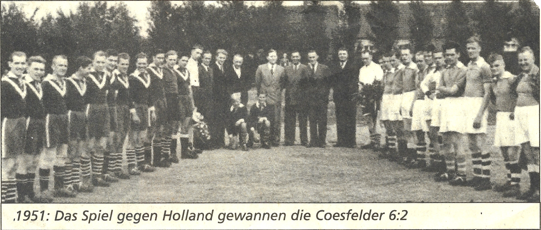 Zeitungsfoto auf dem zwei Fußballmannschaften links und rechts angeordnet sind, alle lächeln. In der Mitte stehen einige anzugtragende Menschen. Die Bildunterschrift lautet: 1951: Das Spiel gegen Holland gewannen die Coesfelder 6:2